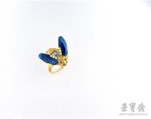 戒指表,瑞士日内瓦,约1910年。该表为金质表壳,采用机雕金胎透明珐琅工艺,切面圆钻和切面圆形蓝宝石,镀银表盘;内置德国银椭圆形桥架式机芯,表面珍珠圆点打磨,采用杠杆式擒纵系统,未截断双金属螺丝平衡摆轮,平游丝,快慢针